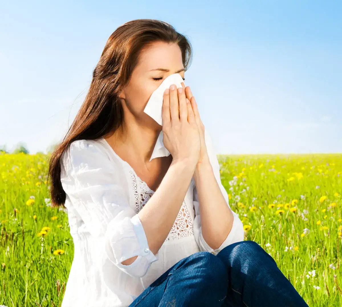 Ein Frau auf einer Wiese putzt sich die Nase