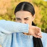 Eine Frau nießt auf Ihr Handgelenk