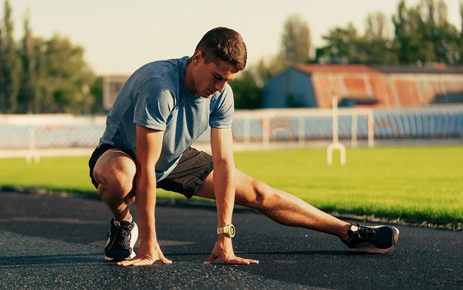 Gut aufwärmen beim Training Ein Mann macht auf einer Laufbahn einer Sportstätte Dehnübungen