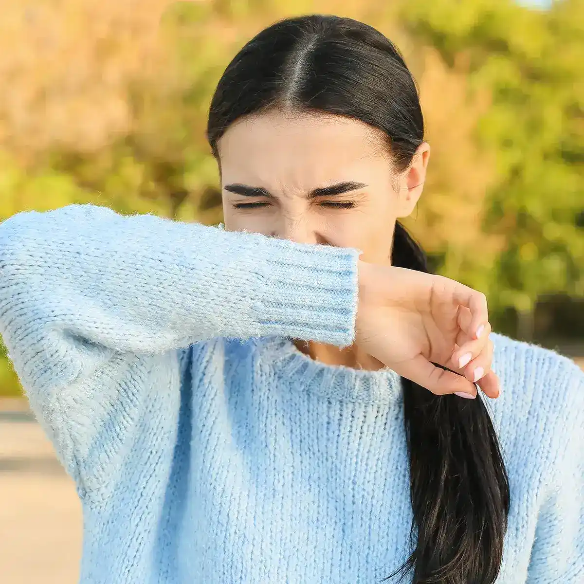 Eine Frau nießt auf Ihr Handgelenk