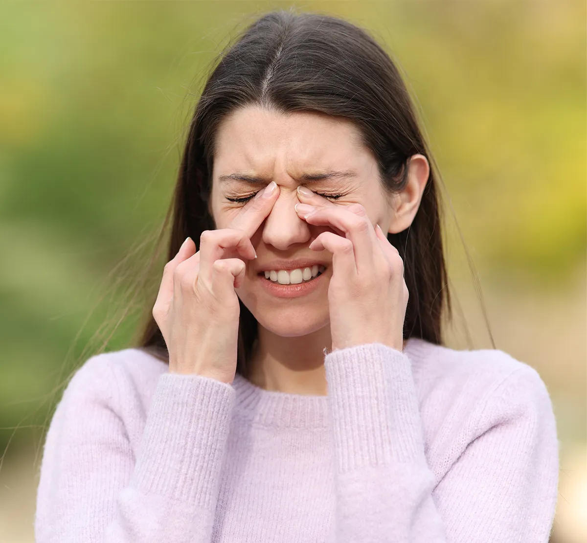 Eine Frau mit geschlossenen Augen hält sich den Augen-/Nasenbereich