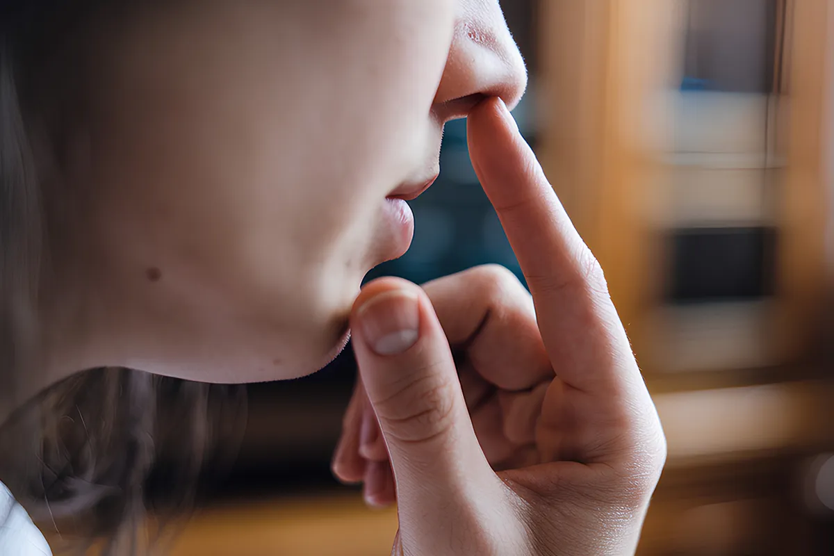 Nebenwirkungen Heuschnupfenmittel Großaufnahme Zeigefinger in Richtung Nasenloch